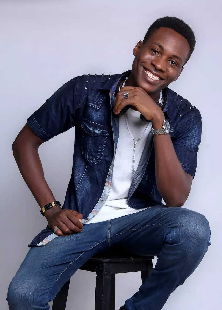 Young adult smiling indoors in casual denim outfit, exuding relaxed style.