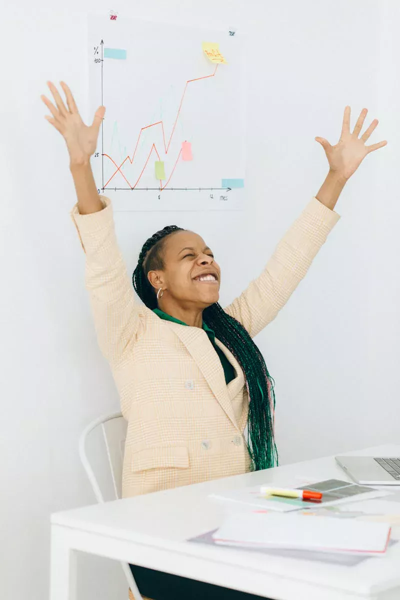 Confident businesswoman celebrates success with arms raised in office setting.